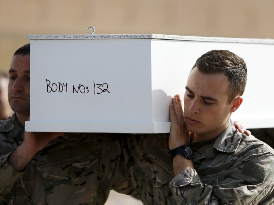 Zwei maltesische Soldaten tragen einen Sarg mit der Aufschrift "Leiche Nummer 132"