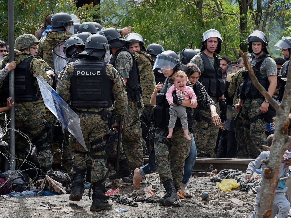 Eine mazedonische Polizistin hält ein Flüchtlings-Baby im Arm 