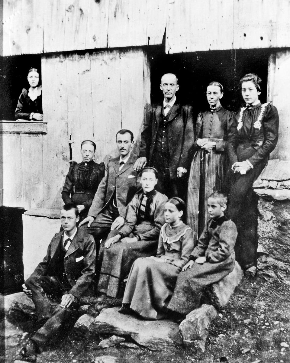 Altes Schwarzweissfoto: Gruppenbild einer grossen Familie vor einem Haus.