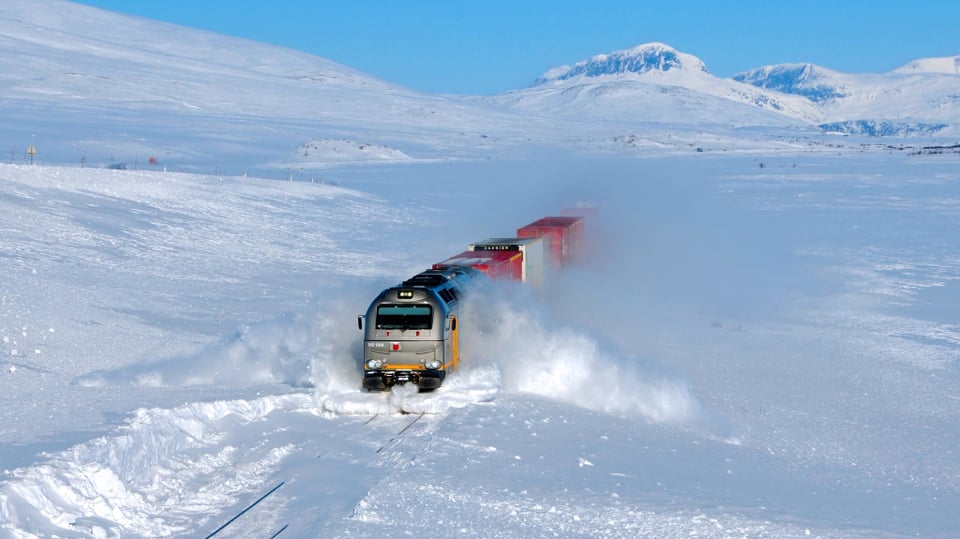 Eine Bahn fährt durch hohen Schnee.