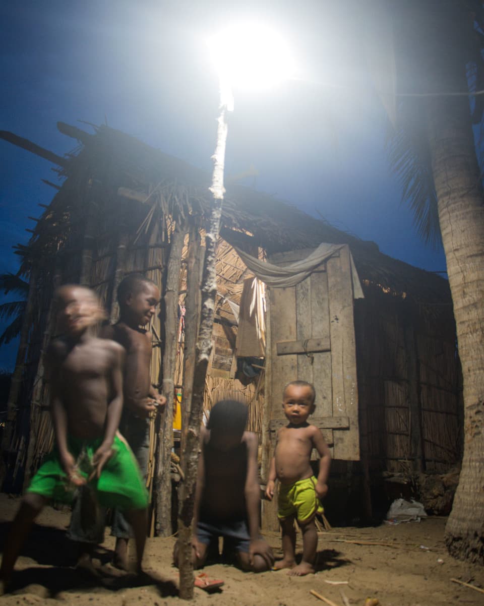 Schwarze Kinder vor einer Hütte, vor der ein Licht brennt. 