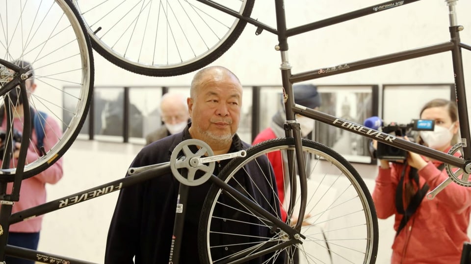 Ai WeiWei steht zwischen einer Skulptur aus Velos.