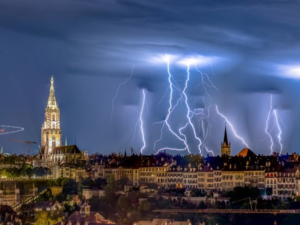 Nachthimmel über Bern mit einigen Blitzen am Horizont, die auf der Erdoberfläche einschlagen.