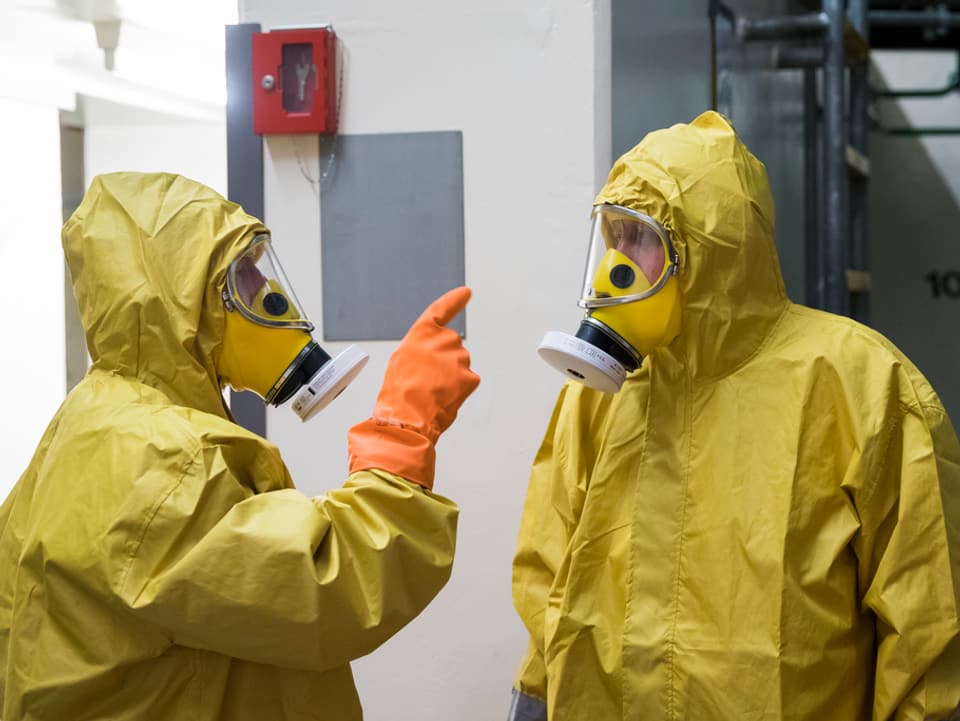 Die Mitarbeitenden tragen gelbe Schutzanzüge, eine Maske und Handschuhe.