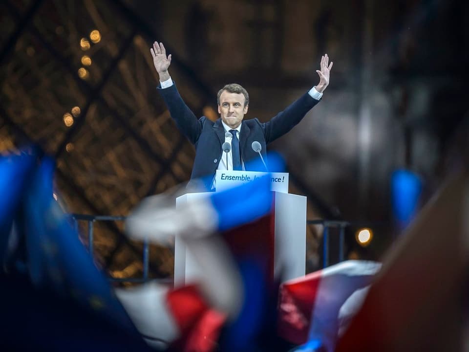 Macron reckt die Arme hoch bei seinem Wahlsieg.