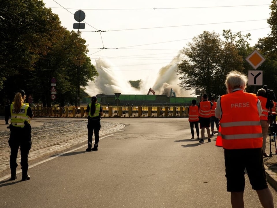 Journalisten und Polizisten sehen auf das gefallene Monument in Riga.