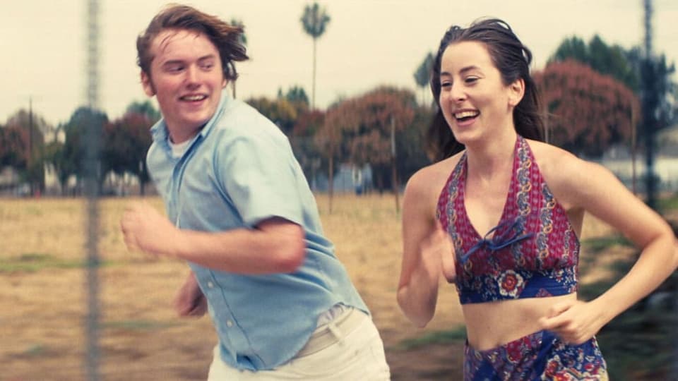 Ein Junge und eine junge Frau rennen und lachen.