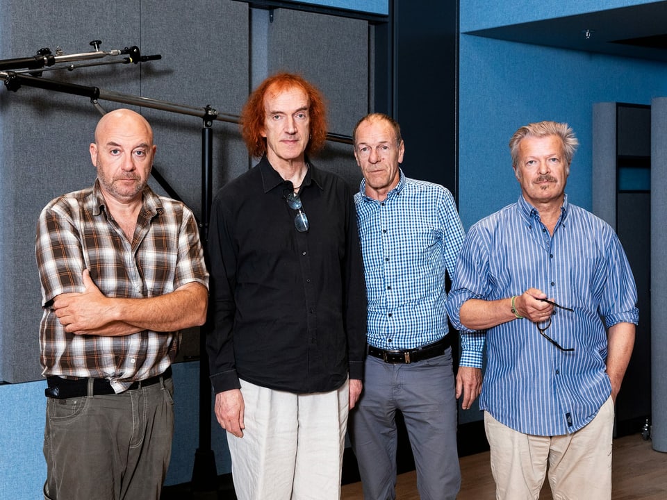 Vier Männer nebeneinander in einem Radiostudio.