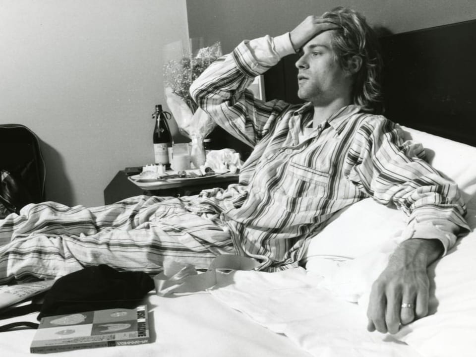 Kurt Cobain liegt in einem Pyjama auf dem Bett