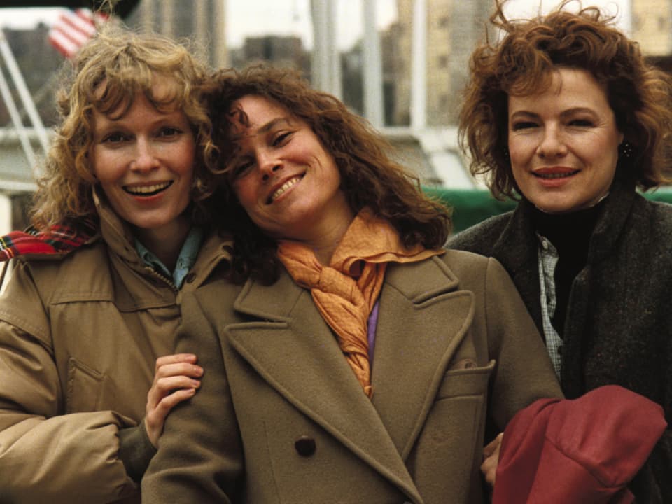 Drei Frauen in Mänteln lachen.