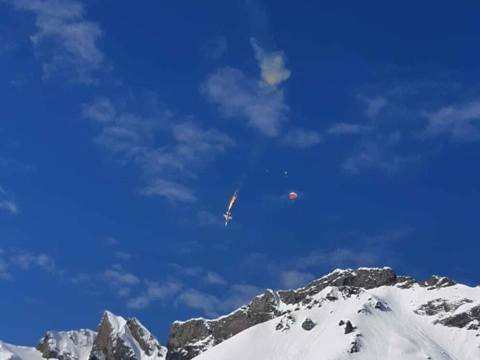Der Absturz der F5 Tiger Maschine auf der Melchsee-Frutt. Flammen, Rauch und der Fallschirm des Piloten sind sichtbar.