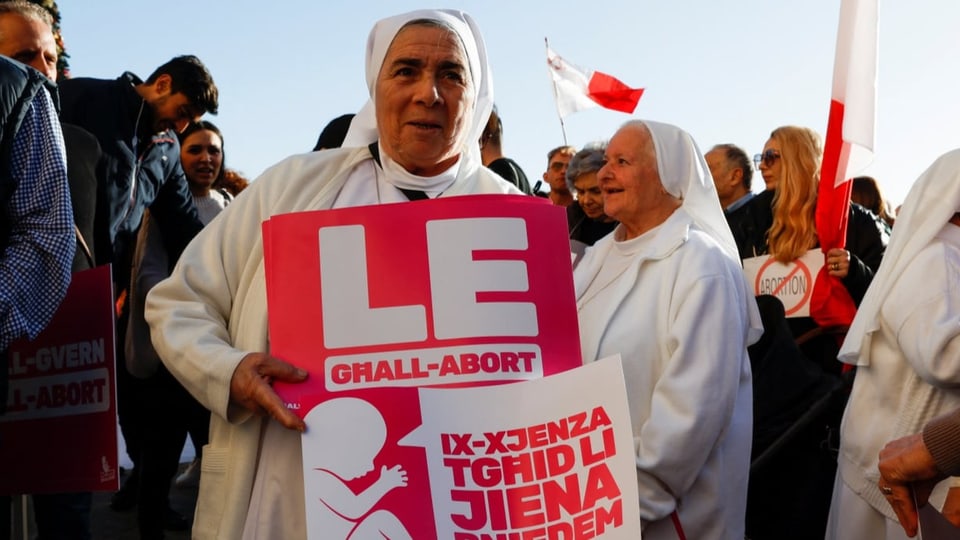 Eine Nonne hält ein Schild gegen Abtreibung in der Hand. Im Hintergrund weitere Demonstrierende.