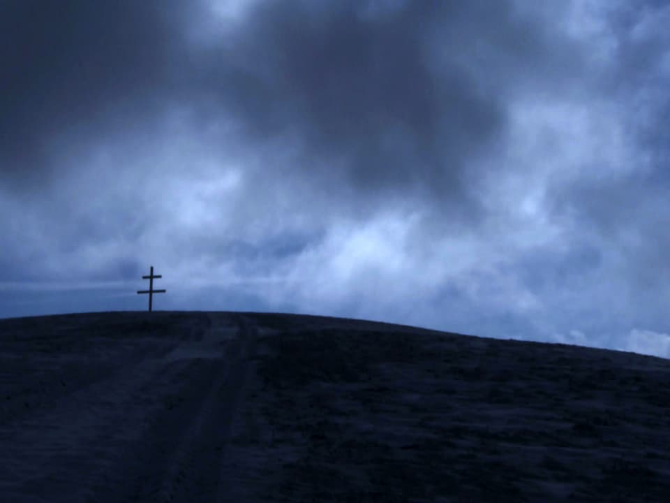 Landschaft bei Escholzmatt im Entlebuch, einer der Schauplätze im Film «Arme Seelen»: Ein Kreuz auf dem Berg, umgeben von dunklen Wolken.