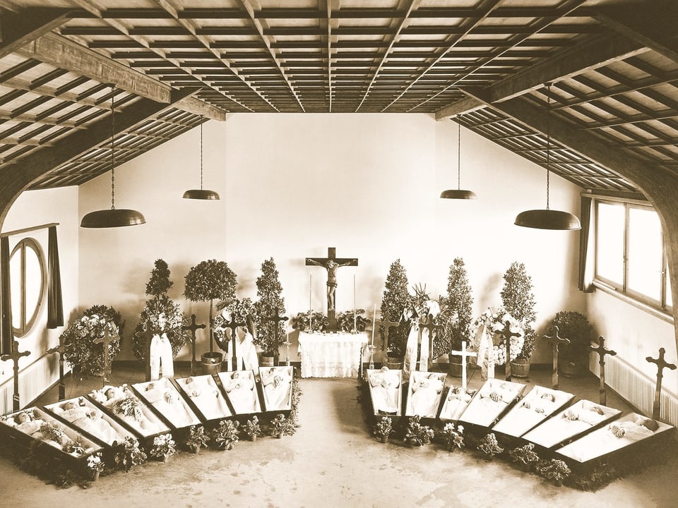 Alte sepiafarbene Fotographie: 13 augestellte Holzsärge in einer Kirche. 