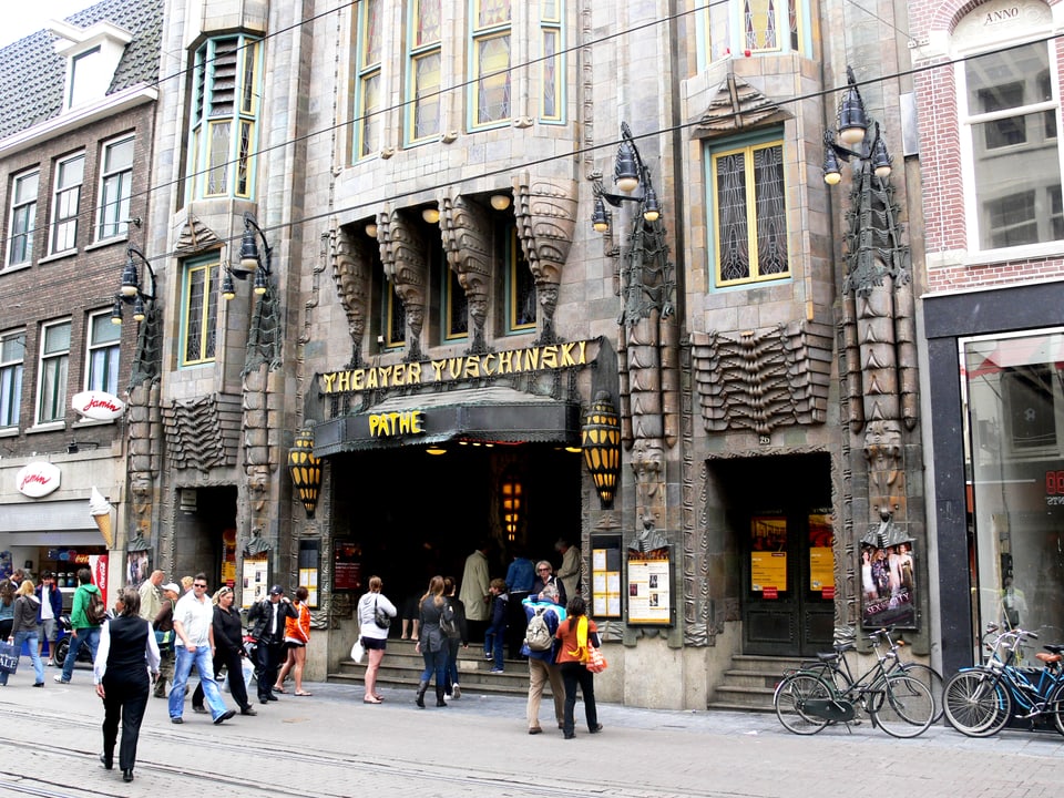 Der Eingang des Theaters und ein Teil der Fassade, davor Theaterbesucher.