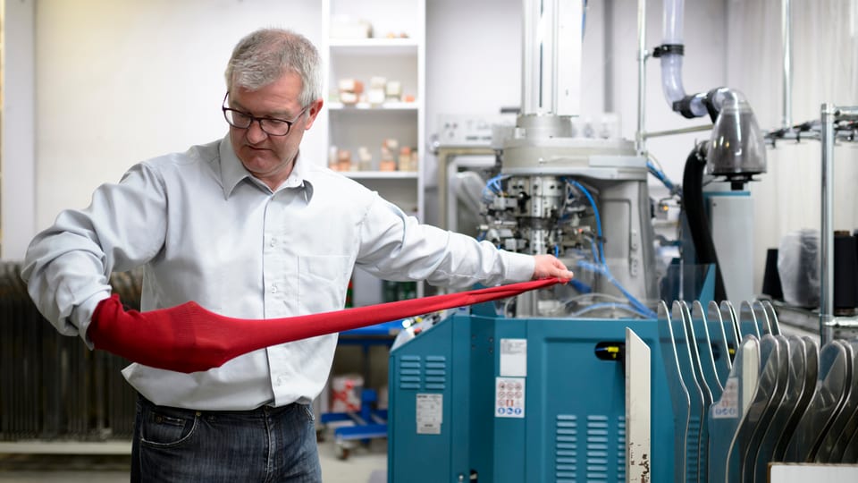 Reneé Tanner mit Sockenstoff, der aus einer Fabrikationsmaschine kommt.