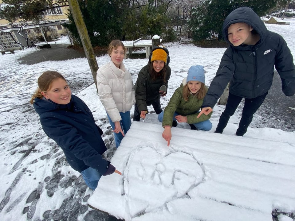 Kinder haben ein Herz in den Schnee gezeichnet und darin SRF geschrieben