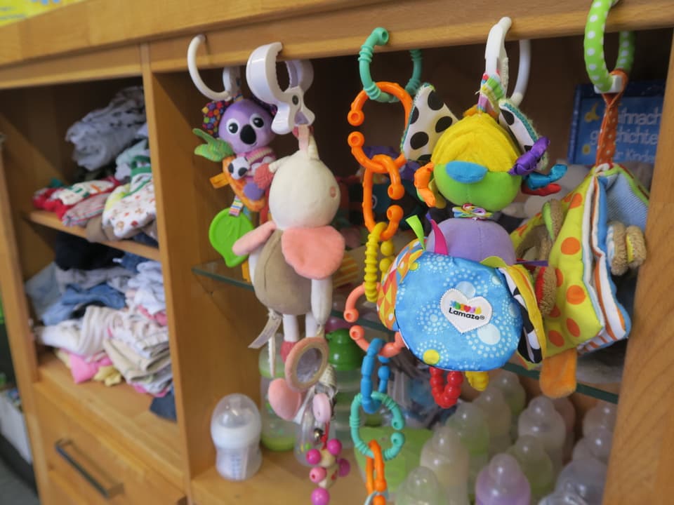 Babyspielsachen hängen an einem Holzregal.