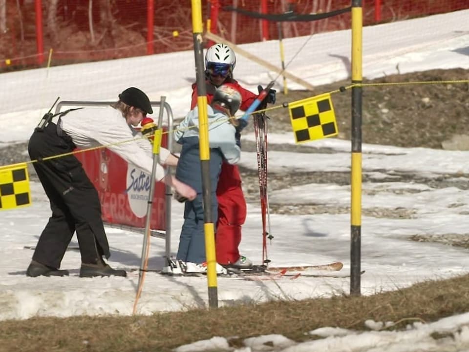 Mann gibt Bügel an Skifahrerinnen