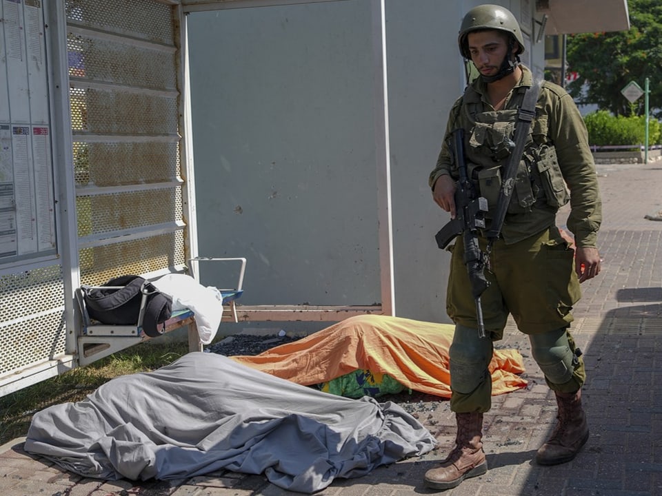 Ein israelischer Soldat neben zwei getöteten Israeli in der Stadt Sderot.