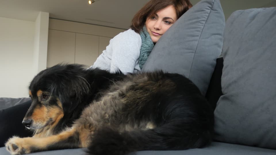 Jessica sitzt auf dem Sofa mit einem Hund.