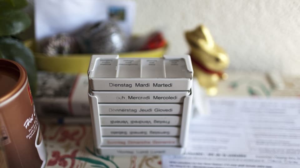 EIne Schachtel Medikamente steht auf einem Tisch bereit. Beschriftet nach Wochentagen.