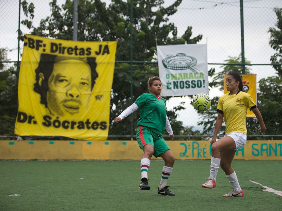 Zwei Frauen spielen an einem Match, hinter ihnen hängen Transparente.