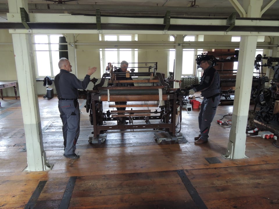 Männer platzieren Webstuhl am richtigen Ort in Fabrikhalle