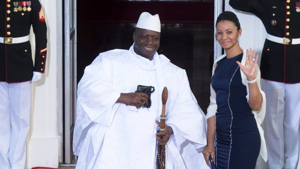 Yahya Jammeh sitzt, daneben steht eine frau