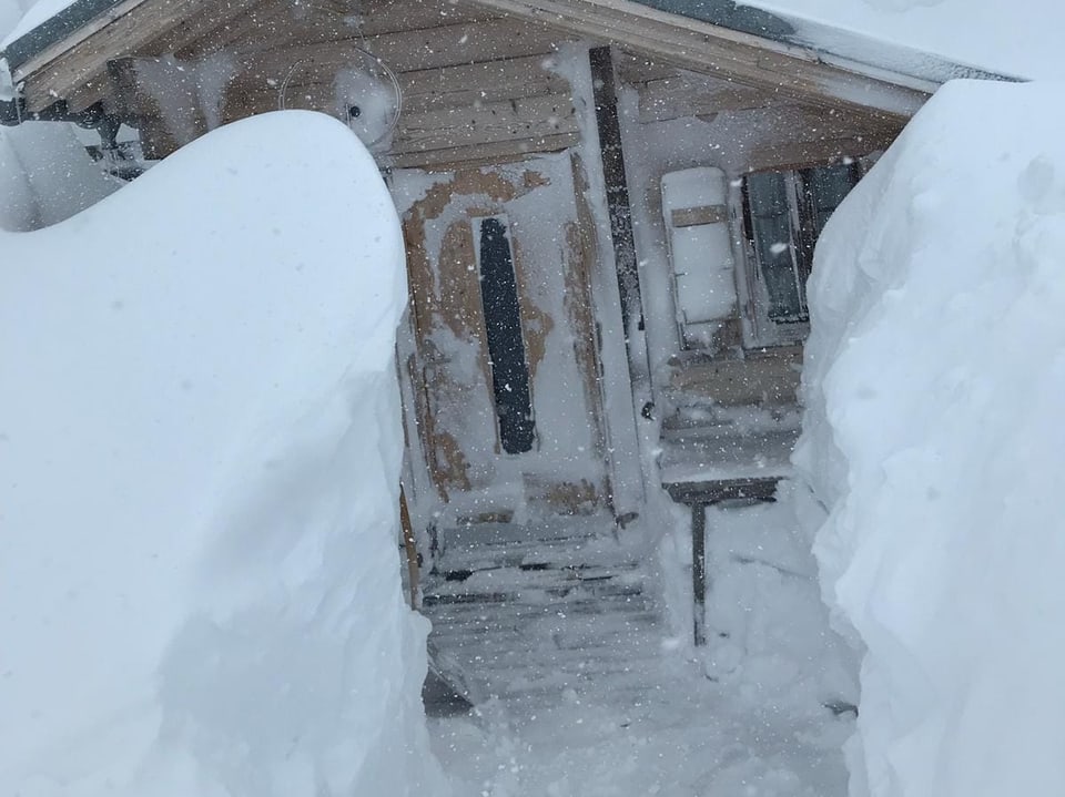 Viel Schnee vor einer Hütte.