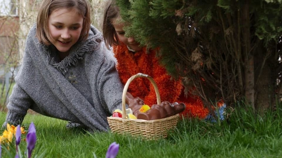 Viele Fragen! Zwei Mädchen suchen ein Osternest im Garten