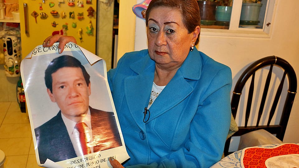 Eine Frau hält ein Plakat mit dem Porträt ihres Bruders hoch.