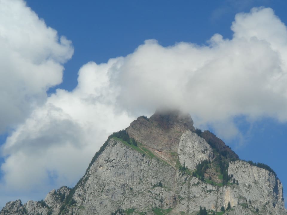 Berggipfel im Sommer mit eine Wolke ganz oben. Die Blumenkohlwolken beginnt auf Gipfelhöhe und wächst in den Himmel. 
