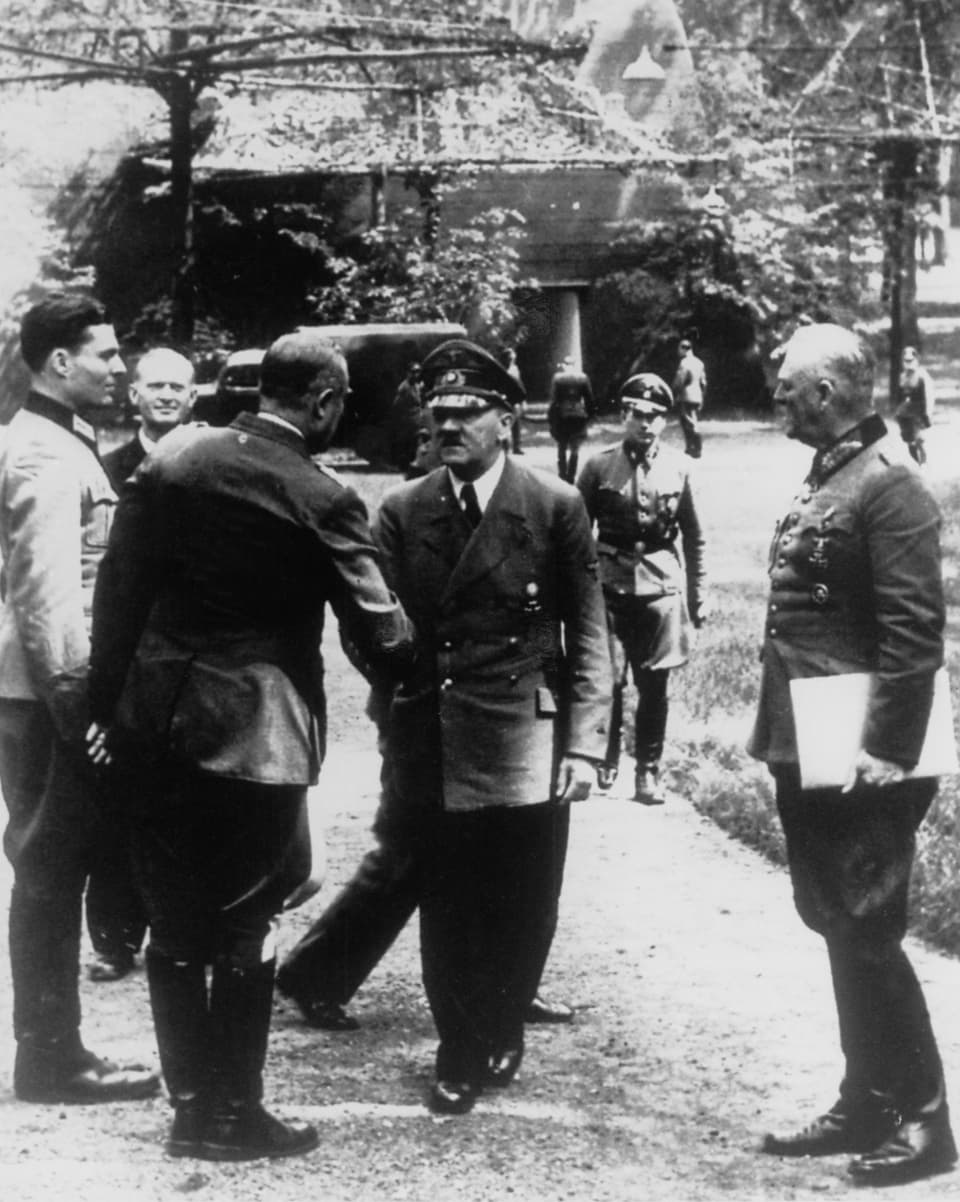 Historisches Foto: hitler in Uniform, reicht einem anderen Mann die Hand. Daneben, in heller Uniform strammstehend, Stauffenberg.