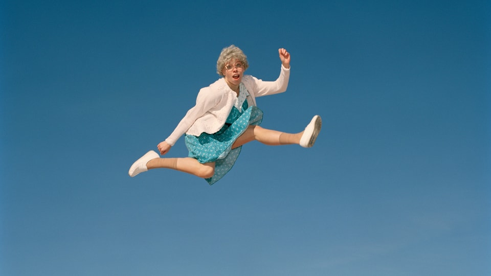 Eine ältere Frau springt in die Luft.