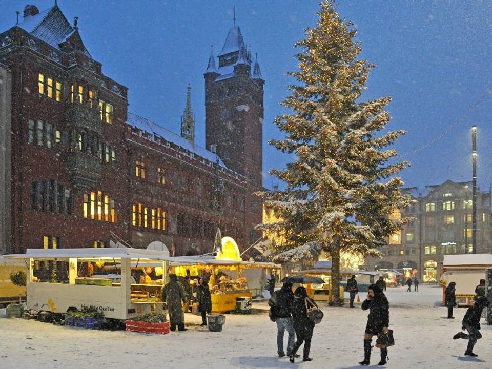 Grosser Weihnachtsbaum vor der Rathausfassade im Schneegestöber.