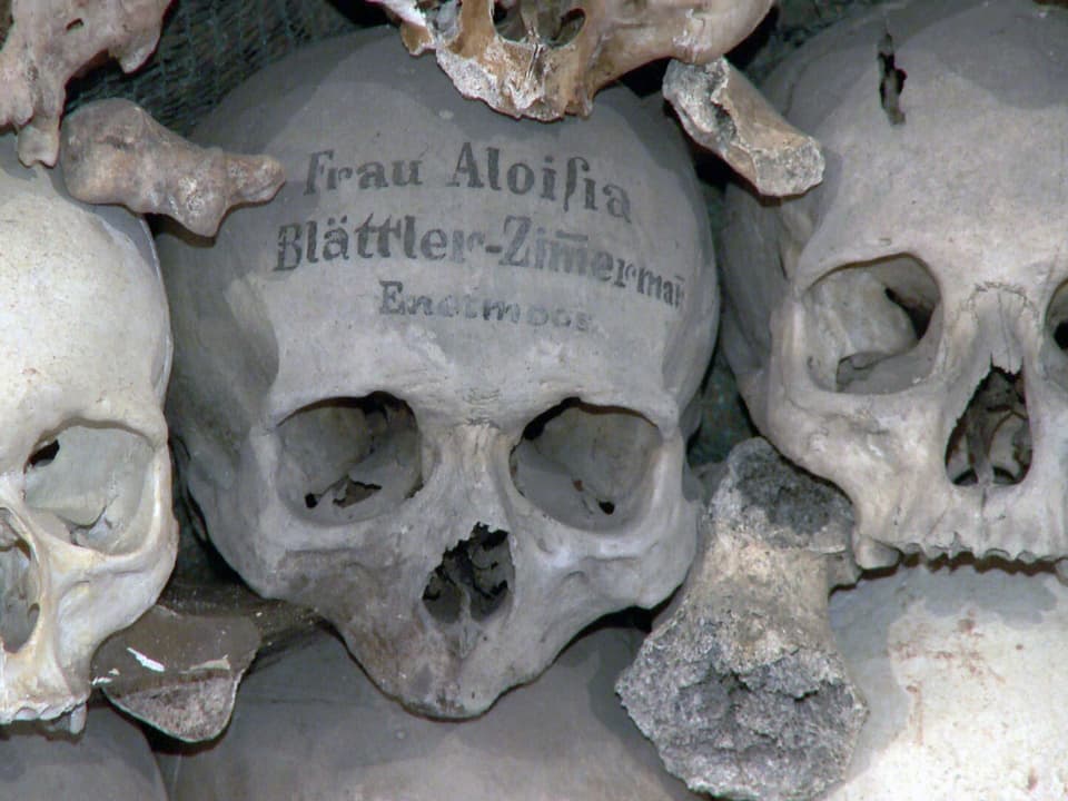 Totenköpfe im Beinhaus von Stans, einer beschrieben mit dem Namen der Verstorbenen.