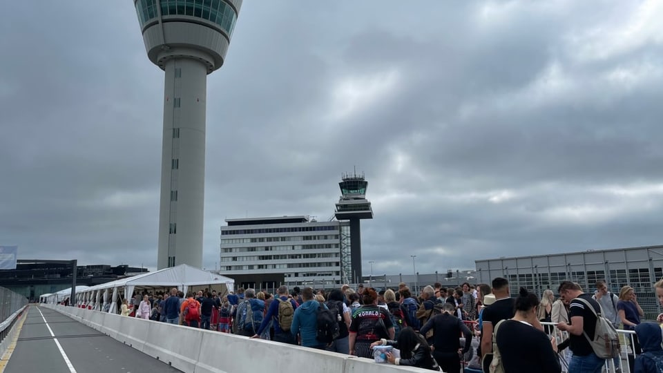 Menschen stehen am Flughafen von Amsterdam an.