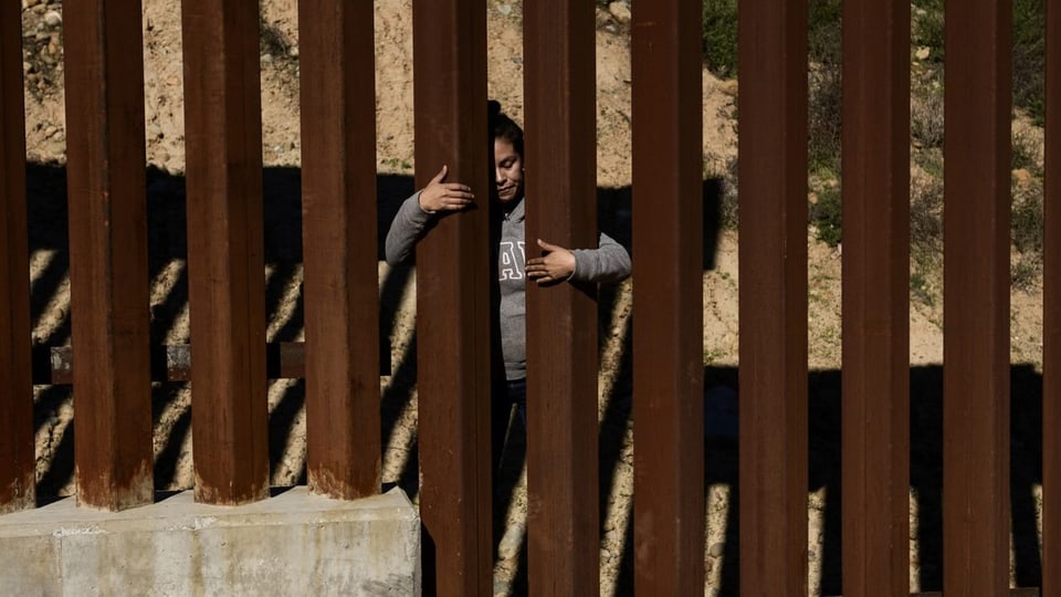 Migrantin vor Grenzzaun bei San Diego