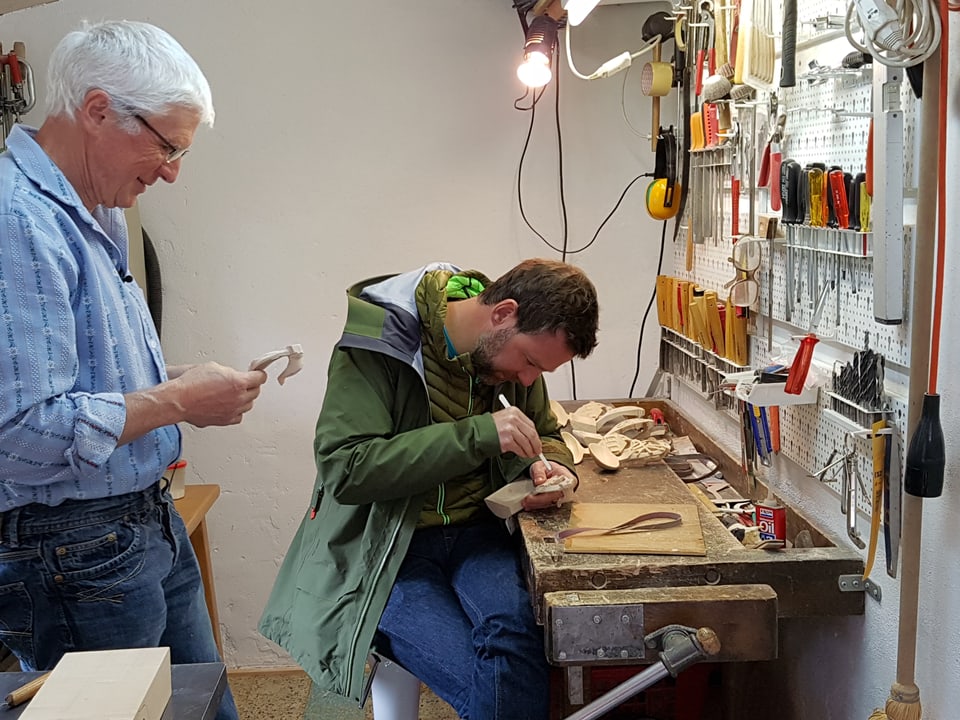 Älterer Mann in Werkstatt zeigt Nik Hartmann, wie Holzlöffel hergestellt werden. 