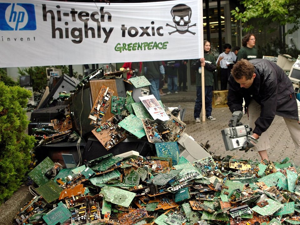 Ein Haufen voller Elektroschrott unter einem Greenpeace-Banner