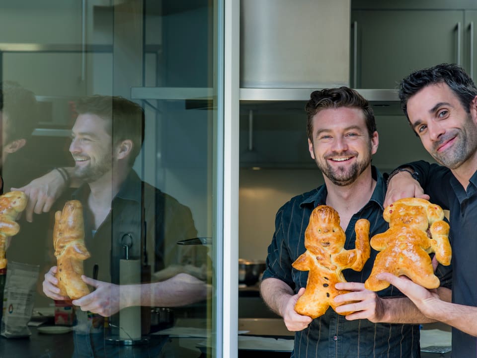 Jann Hoffmann und Philippe Gerber stehen am Küchenfenster und präsentieren ihre goldbraun gebackenen Grittibänzen.