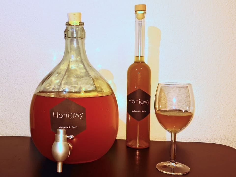 Zwei Flaschen und zwei Gläser gefüllt mit «Honigwy».