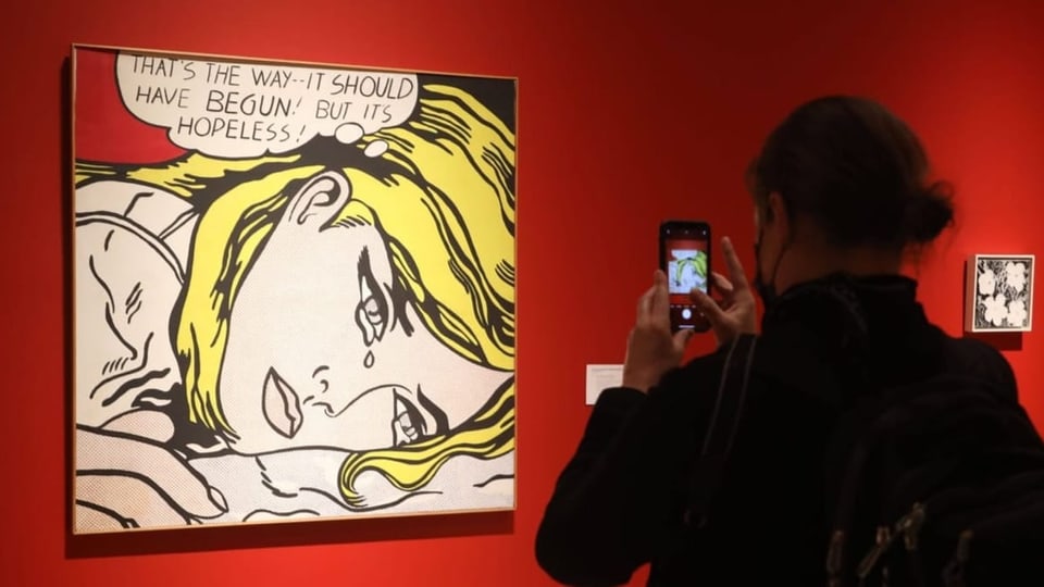 Rückansicht einer Person, die mit dem Smartphone ein Bild von Roy Lichtenstein fotogragfiert