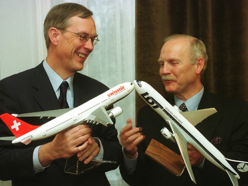 Philippe Bruggiser und der Lot-Präsident Jan Litwinski an einer Medienkonferenz. Sie halten ein Flugzeugmodell ihrer Airline in den Händen.