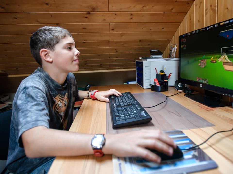 Der 12-jährige Simone sitzt im Holz getäferten Zimmer vor dem Computer, auf dem ein Geschicklichskeitsspiel läuft.