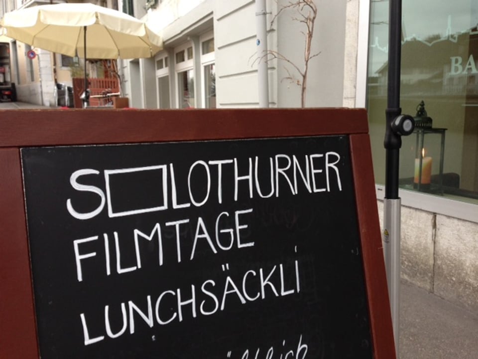 Vor einem Restaurant steht eine schwarze Tafel mit der Aufschrift: «Solothurner Filmtage Lunchsäckli».