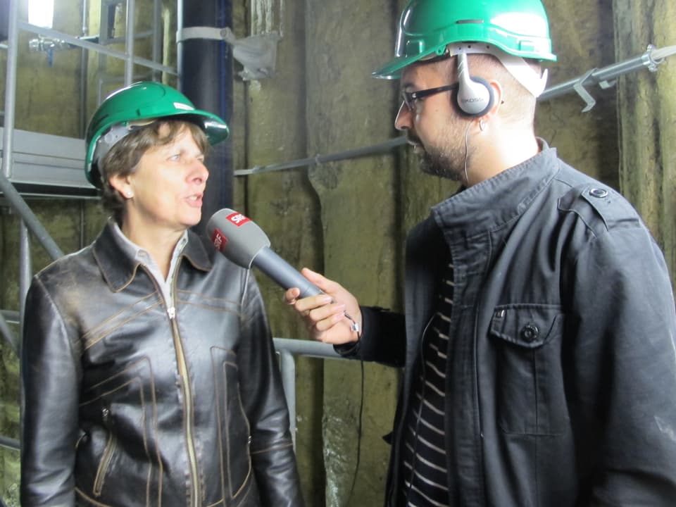 Jolanda Urech in einer Lederjacke und grünem Bauhelm, im Gespräch mit SRF-Journalist Bähram Alagheband.