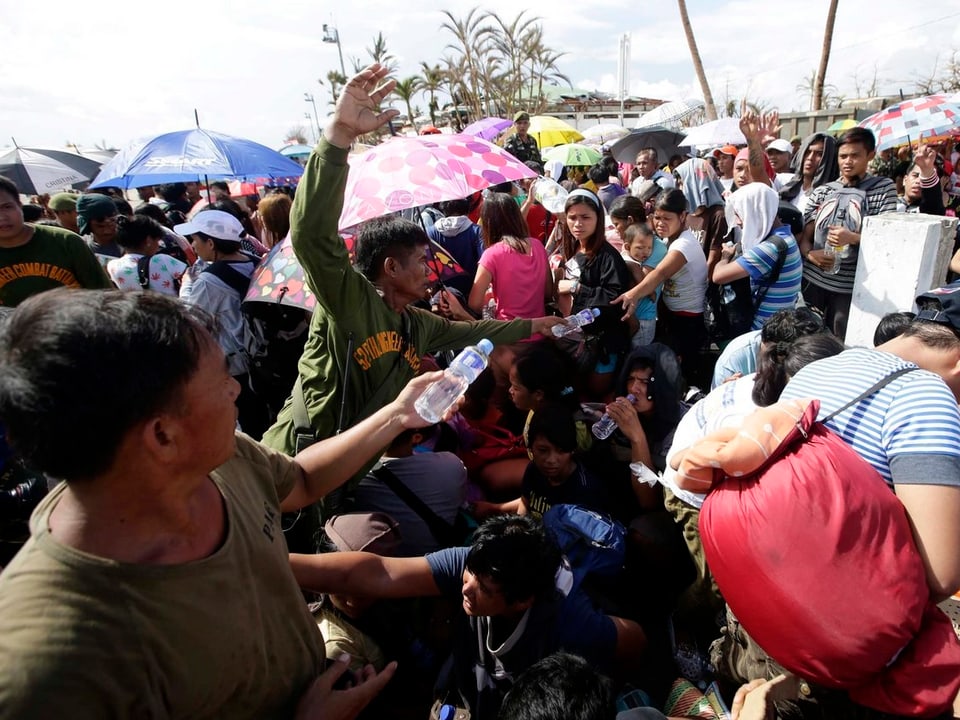 Philippinische Soldaten verteilen Wasserflaschen an die Überlebenden, dabei haben sie sichtlich Mühe, da sich alle drängen. 