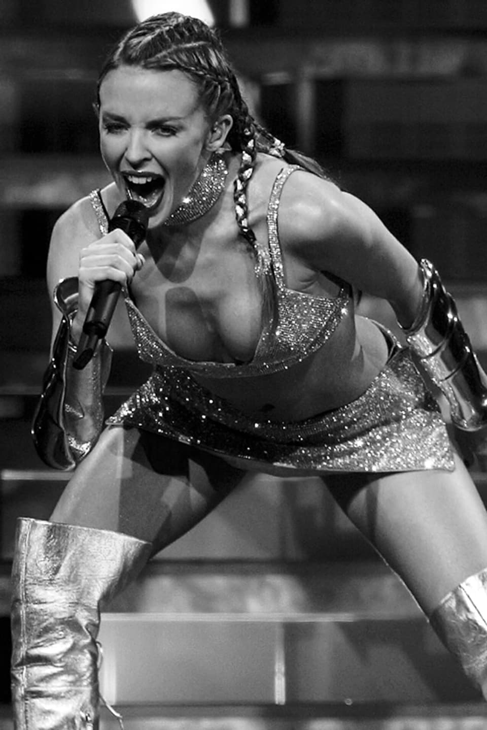 Kylie Minogue beugt sich singend nach vorn gegen das Publikum.